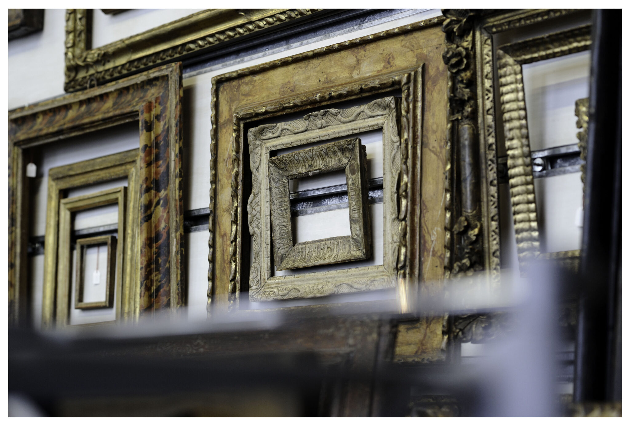 WERNER MURRER RAHMEN-5 - Deutsche Manufakturenstrasse Vielfältige Bilderrahmen in verschiedenen Stilen und Größen, angeordnet an einer Wand.