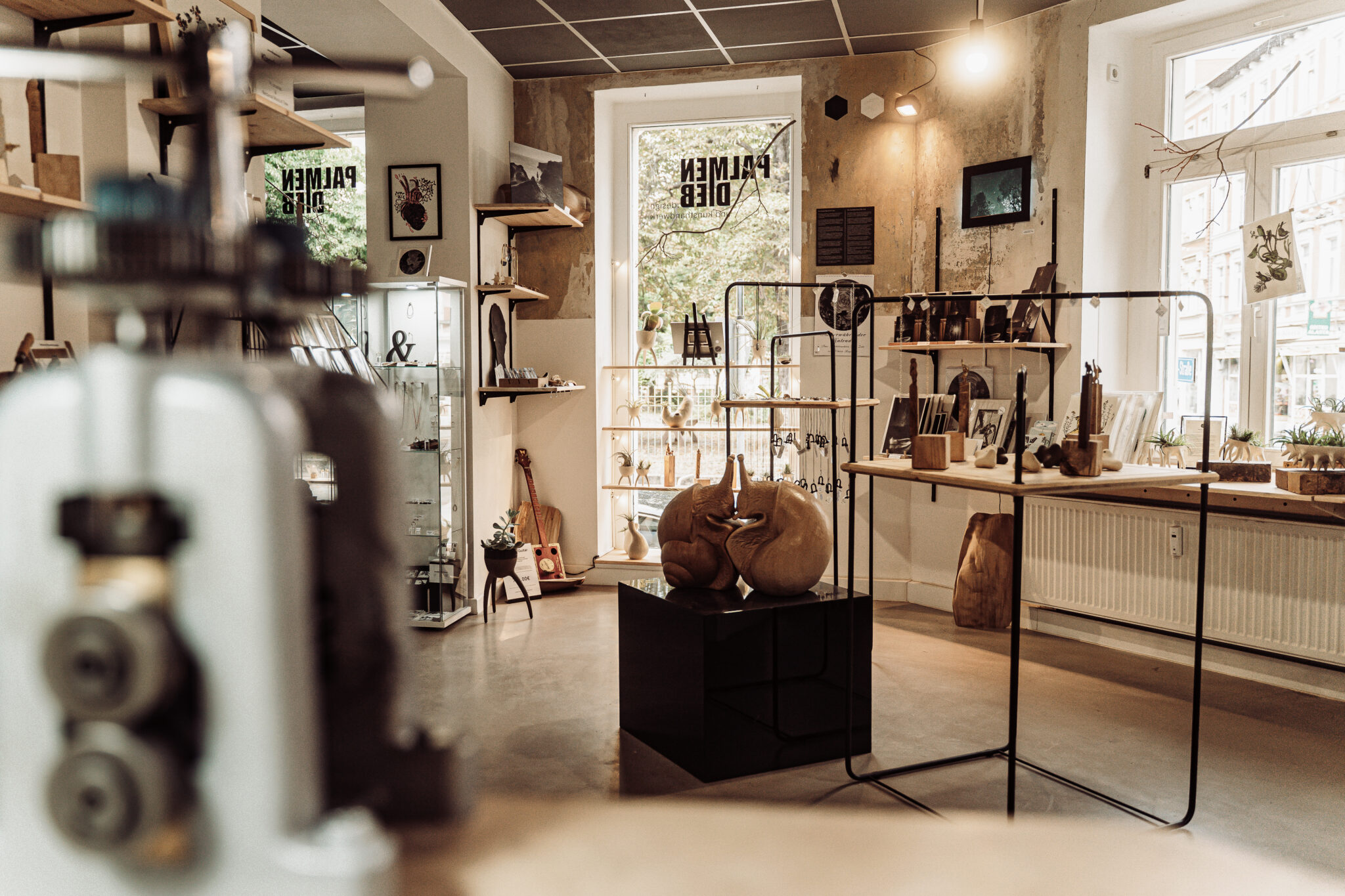 _DSC9559 - Deutsche Manufakturenstrasse Innenansicht eines kreativen Raums mit Holzobjekten und Kunstwerken, Regalen und Fenstern, die Tageslicht hereinlassen.