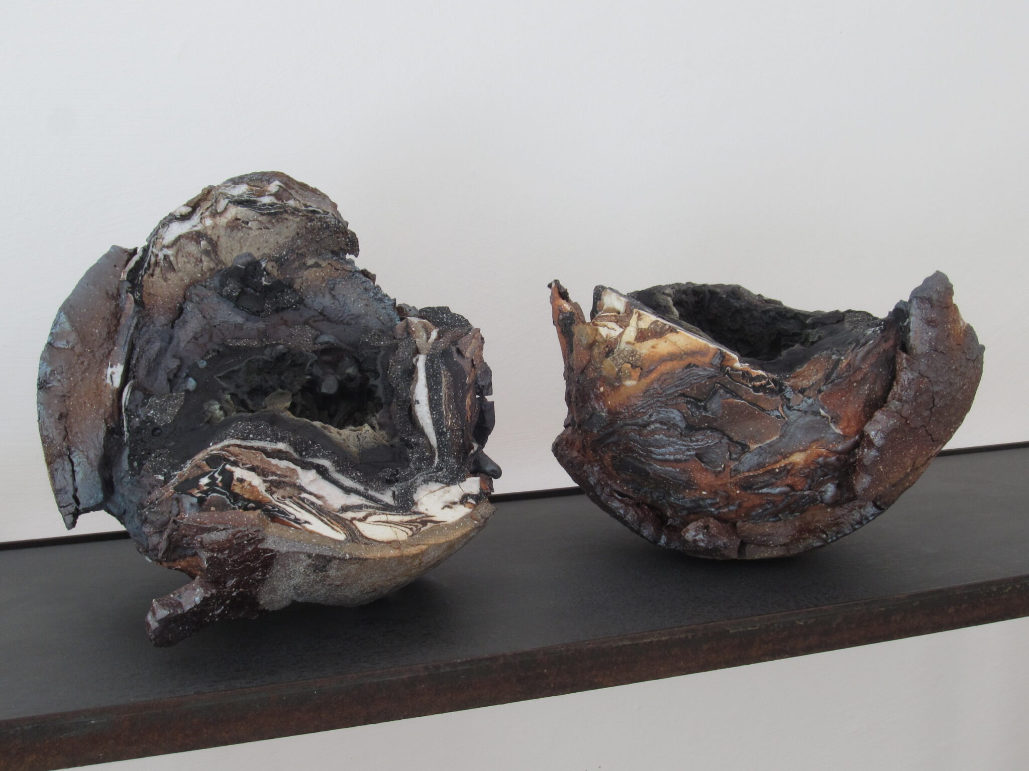 - Deutsche Manufakturenstrasse Zwei keramische Geoden mit unterschiedlichen Oberflächenstrukturen und Farben auf einem Regal.