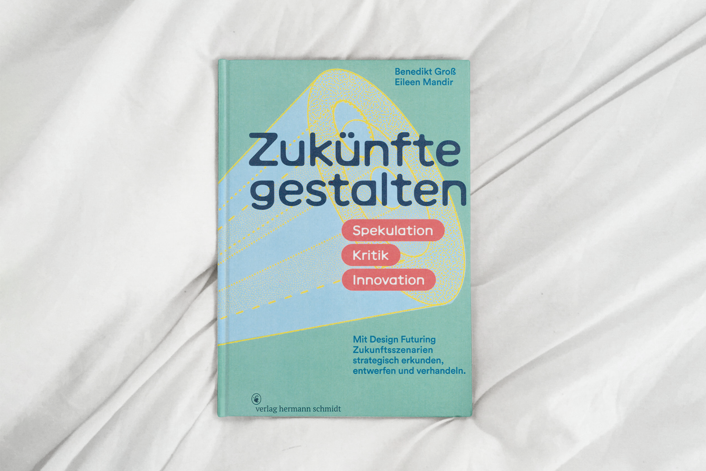 Buchcover mit dem Titel "Zukünfte gestalten" in Türkis, umgeben von Linien, auf einem weißen Bettlaken.