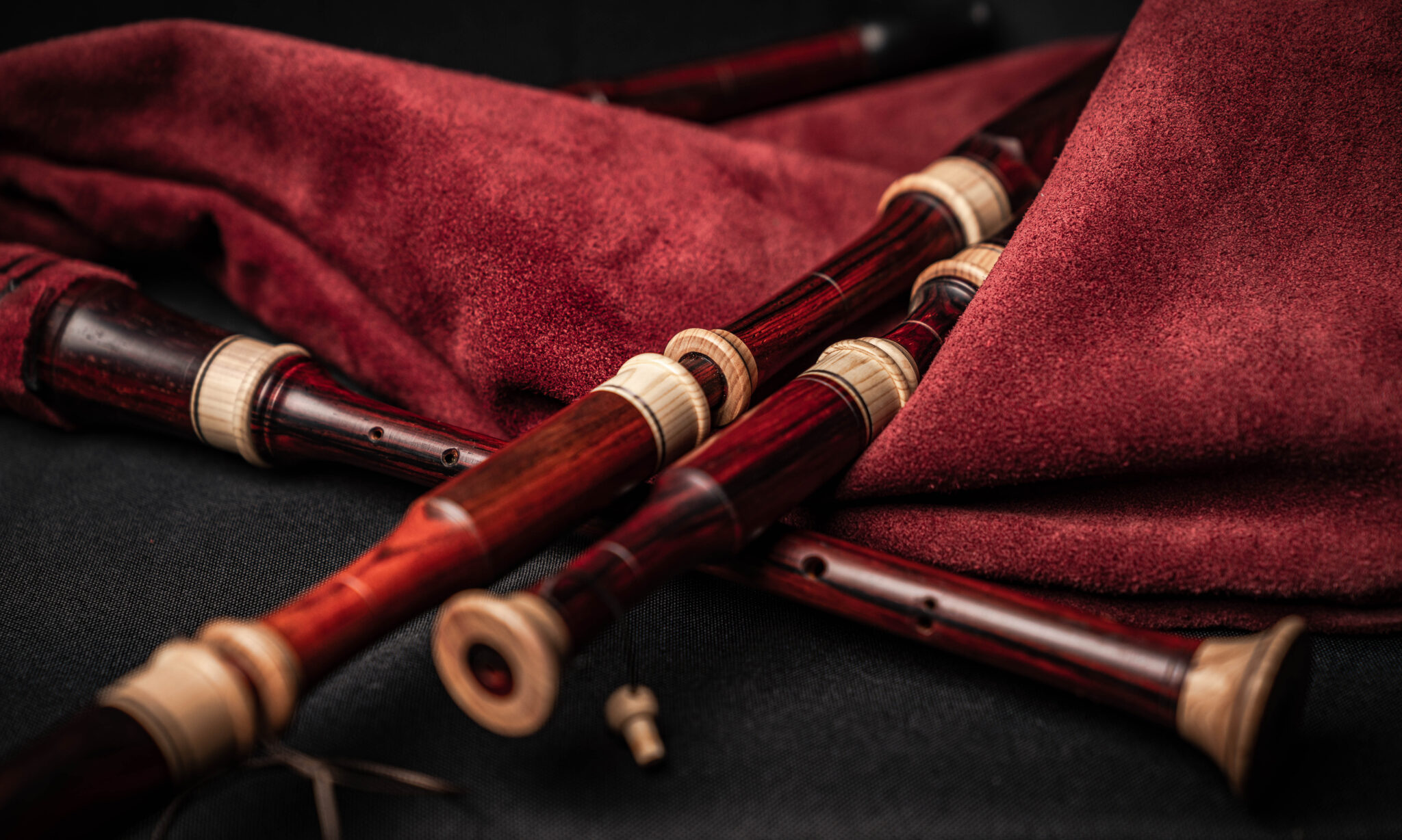 Detailaufnahme von mehreren Holzblasinstrumenten, umgeben von einem roten Tuch auf schwarzem Hintergrund.