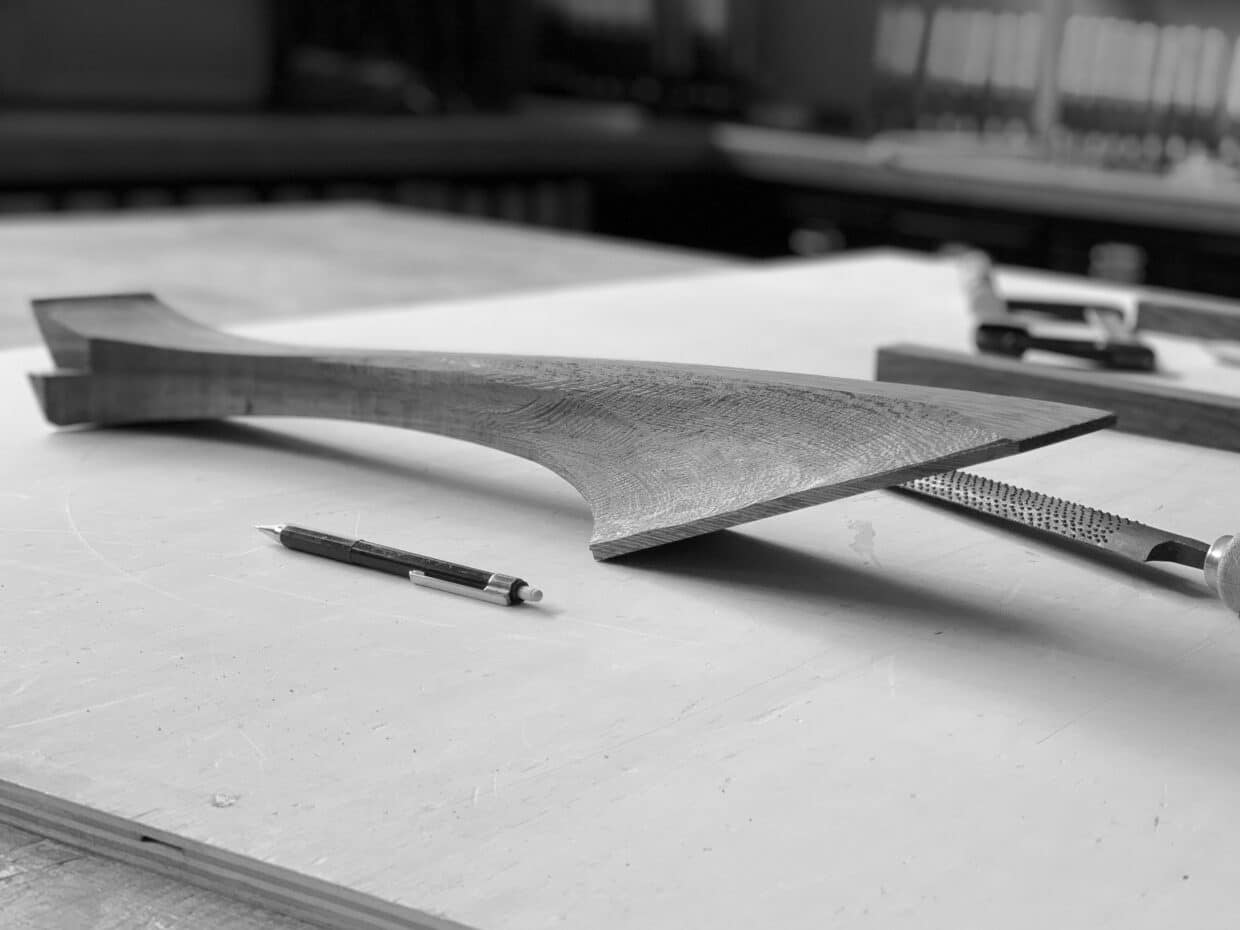 Arbeitsprozess nr 4 - Deutsche Manufakturenstrasse Armlehnen aus Holz liegen auf einer Werkbank, umgeben von Werkzeugen und einem Bleistift.