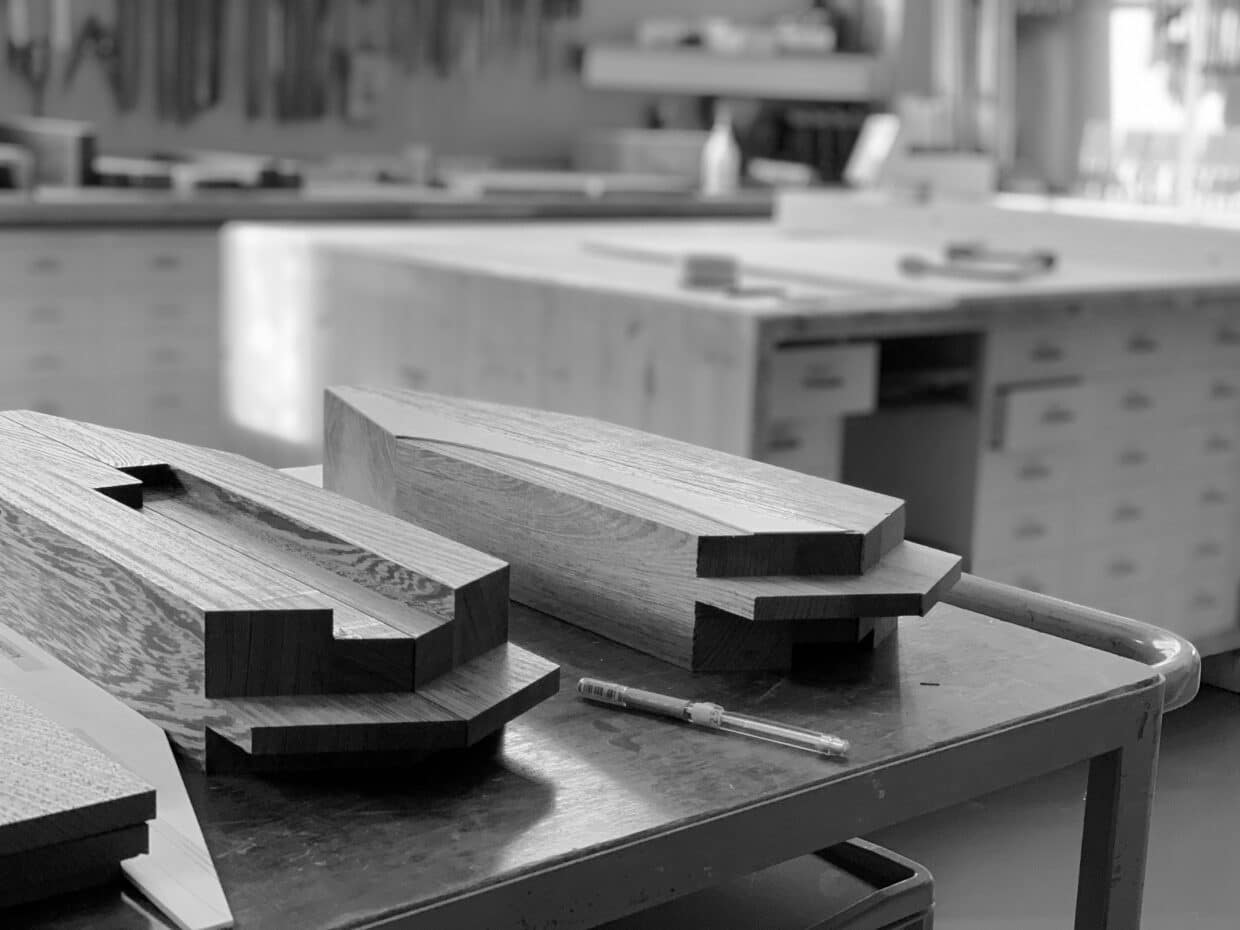 Arbeitsprozess nr 6 - Deutsche Manufakturenstrasse Holzblöcke auf einem Tisch in einer Werkstatt, bereit für die Bearbeitung zu Armlehnen mit präzisen Verbindungen.