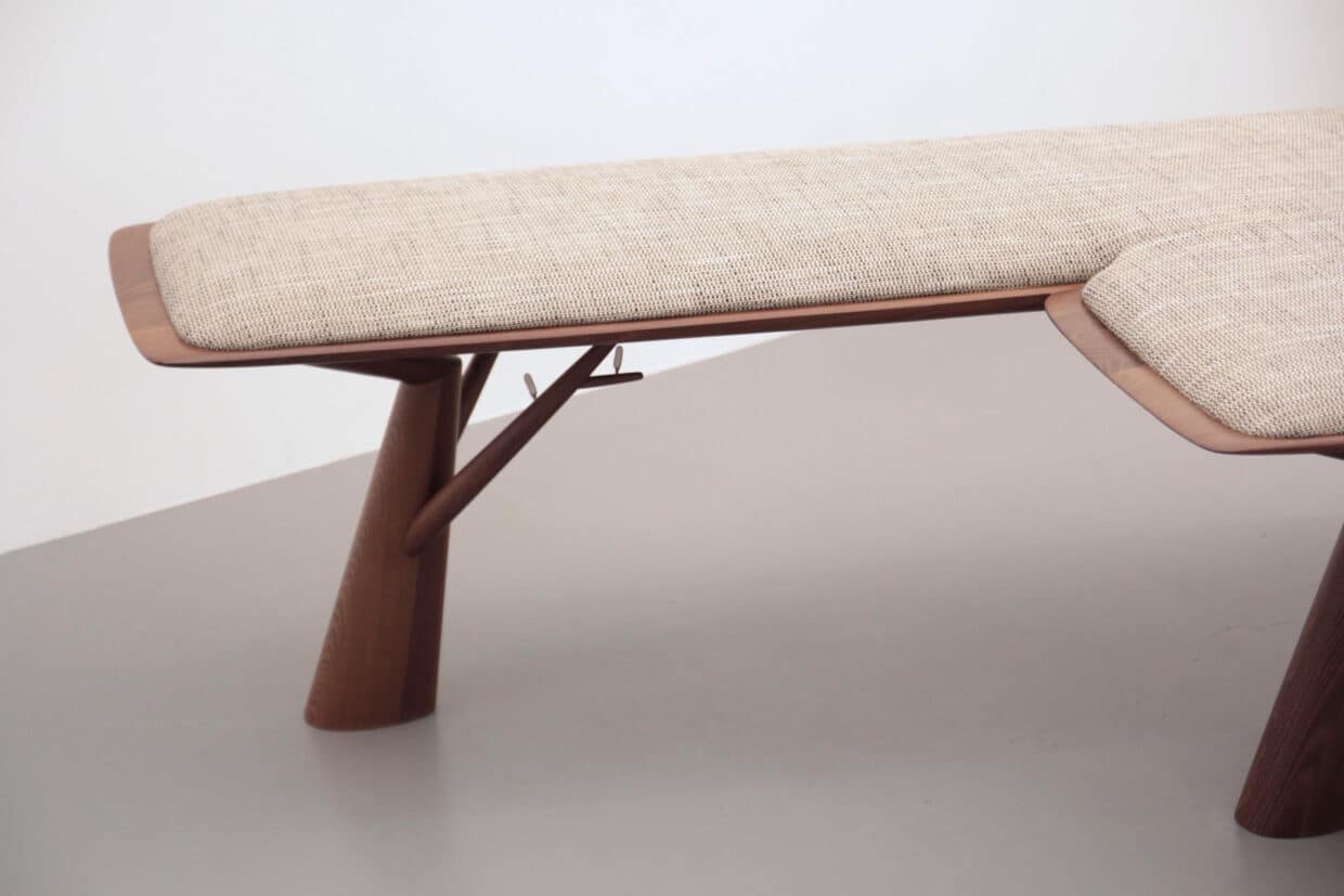 Möbelstücke nr 4 - Deutsche Manufakturenstrasse Detail einer Sitzbank mit einem gepolsterten, hellen Sitz und geschwungenen Holzbeinen.