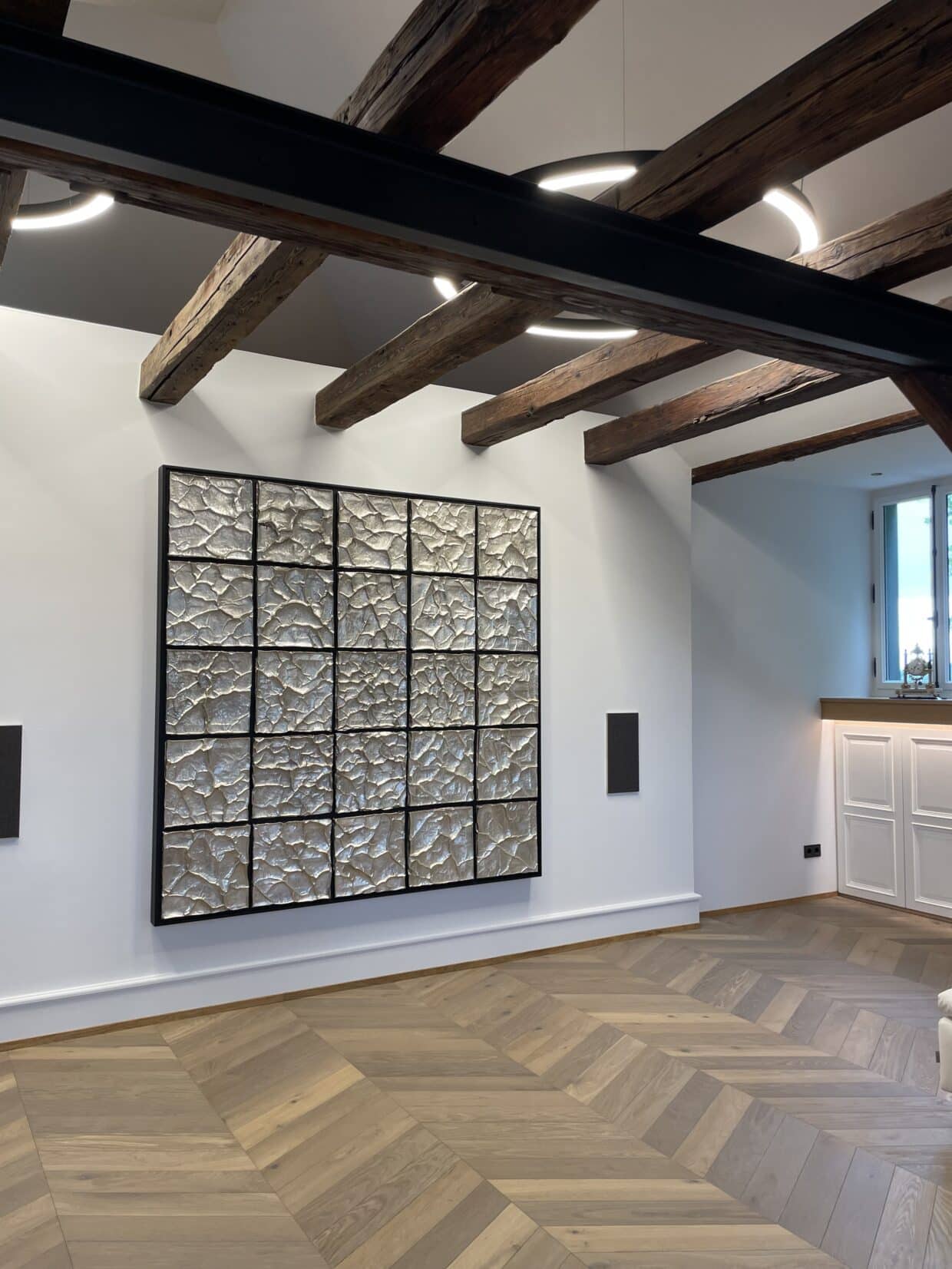 Mosaik Sterling Silber 190x190x3cm - Deutsche Manufakturenstrasse Mosaik aus Sterling Silber in quadratischer Anordnung an einer weißen Wand, umgeben von Holzdeckenbalken und einem hellen...