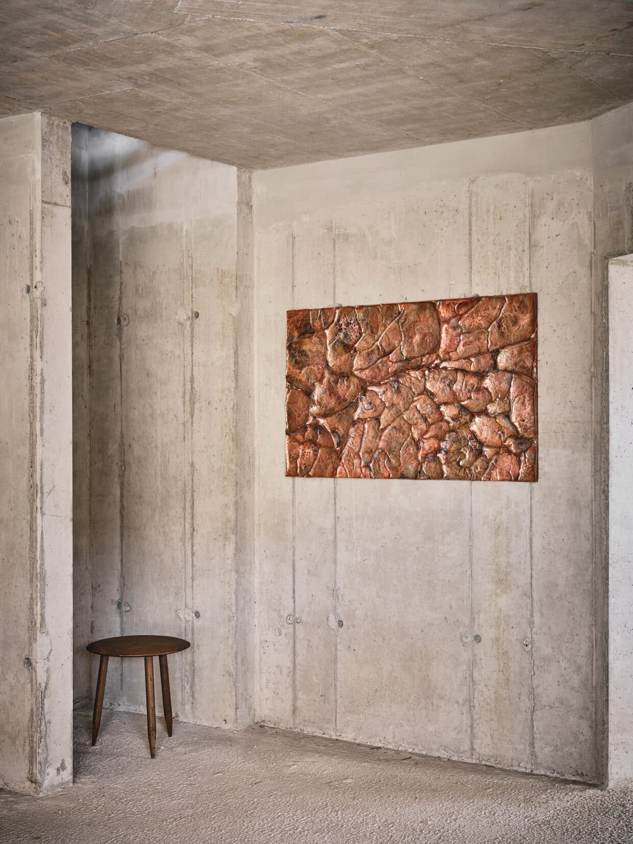 Wandbild Kupfer 185x83x3cm - Deutsche Manufakturenstrasse Wandbild aus Kupfer (185x83x3 cm) an einer Betonwand, daneben ein schlichter Holzstuhl.