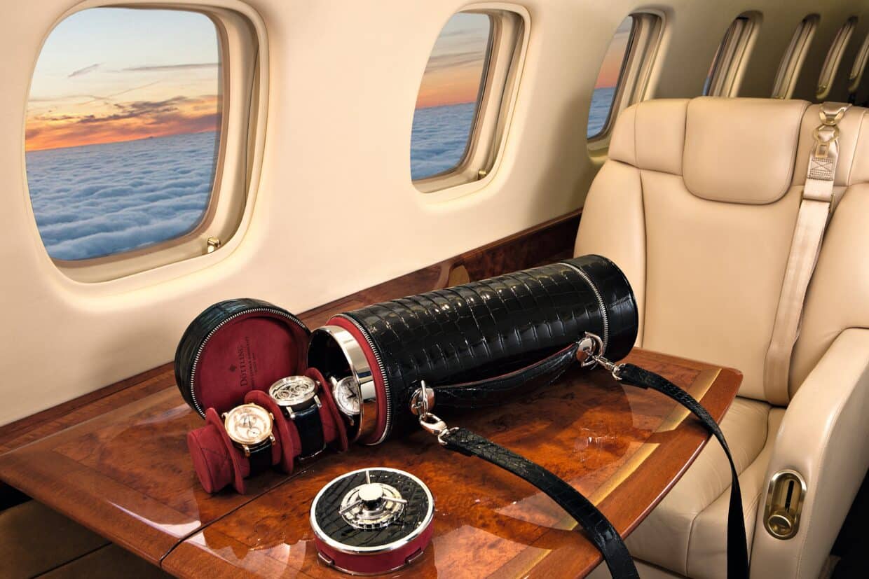 DOETTLING_Guardian_II - Deutsche Manufakturenstrasse Luxuriöse Uhrentasche in einem Privatjet, mit Blick auf den Sonnenuntergang über Wolken.