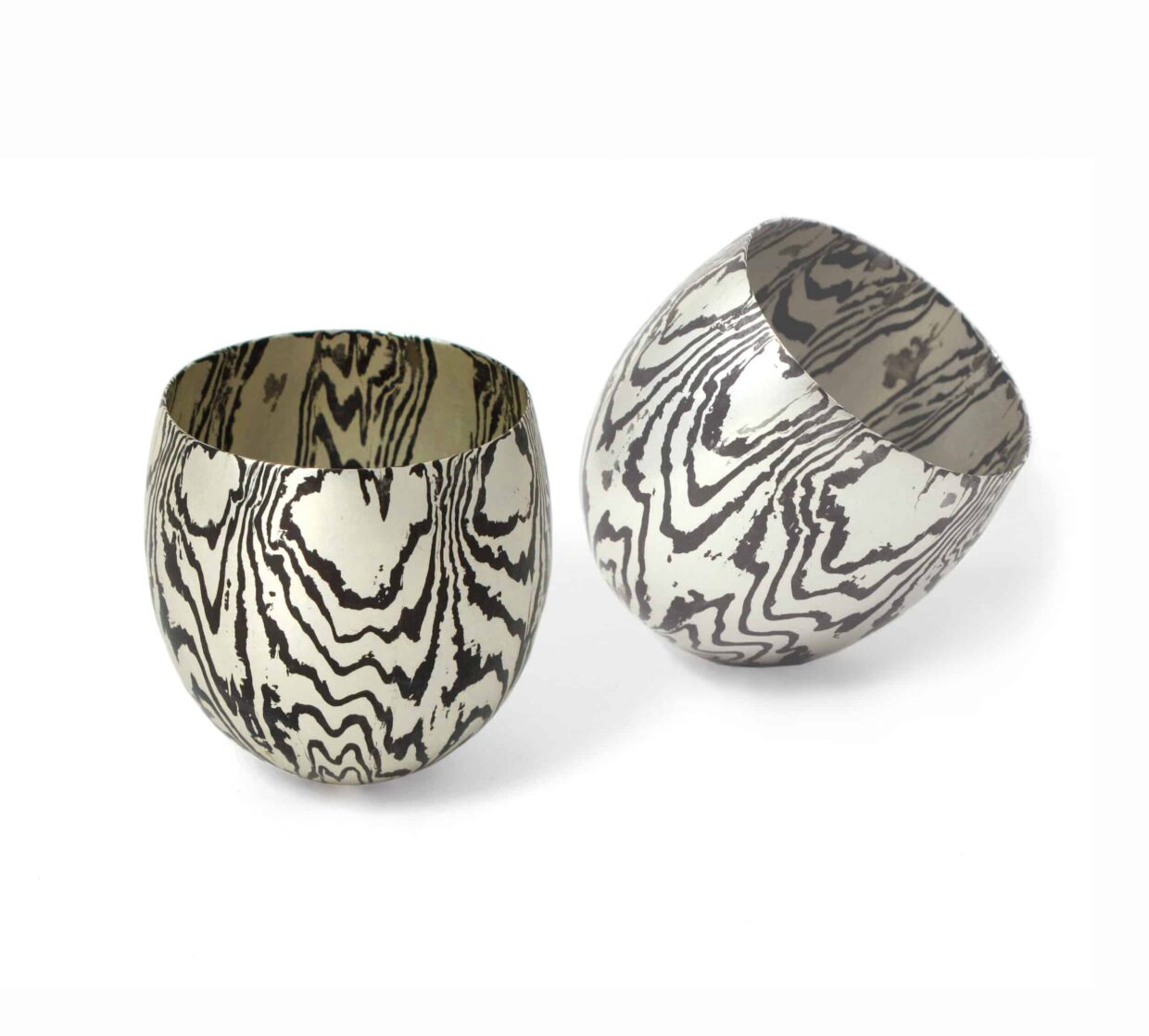Tobias Dingler_Pendelbecher_Mokume Gane - Deutsche Manufakturenstrasse Zwei Pendelbecher aus Mokume Gane mit charakteristischen, gewellten Mustern in Silber und Schwarz.