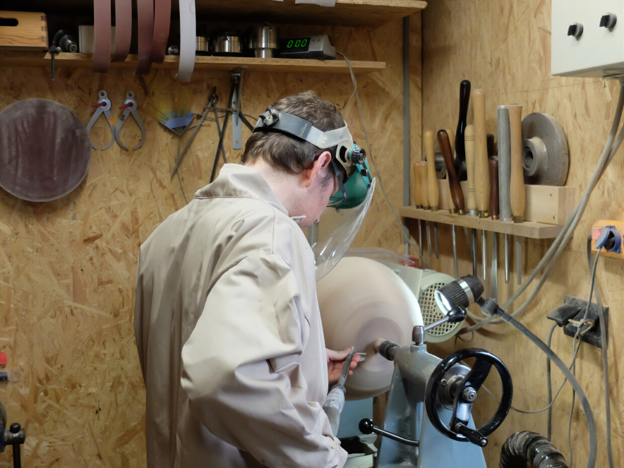 Handwerker in Schutzkleidung arbeitet an einer Holzlathe in einem gut ausgestatteten Werkstattstudio.