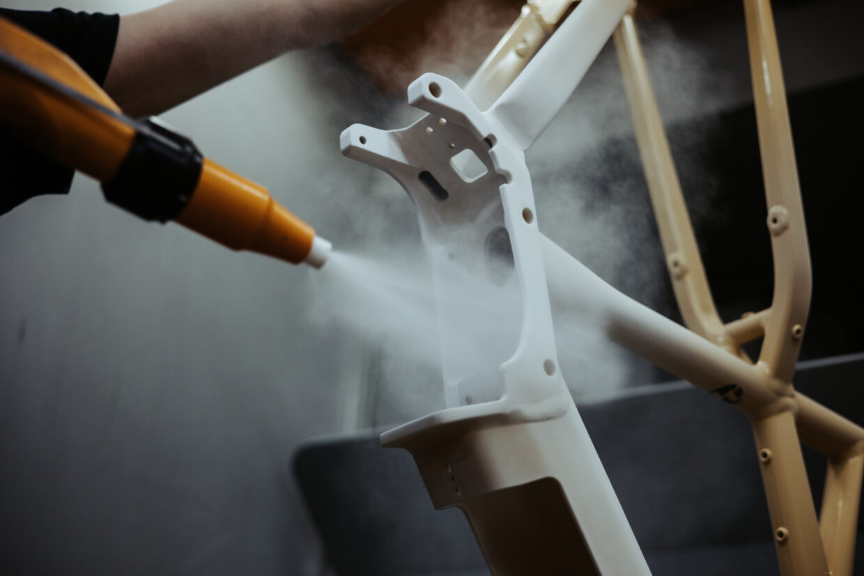 240508_JJANK_ToutTerrain_ManufakturShoot-00433 - Deutsche Manufakturenstrasse Sprühnebel trifft auf einen weißen Fahrradrahmen während des Herstellungsprozesses in der Tout Terrain Manufaktur.