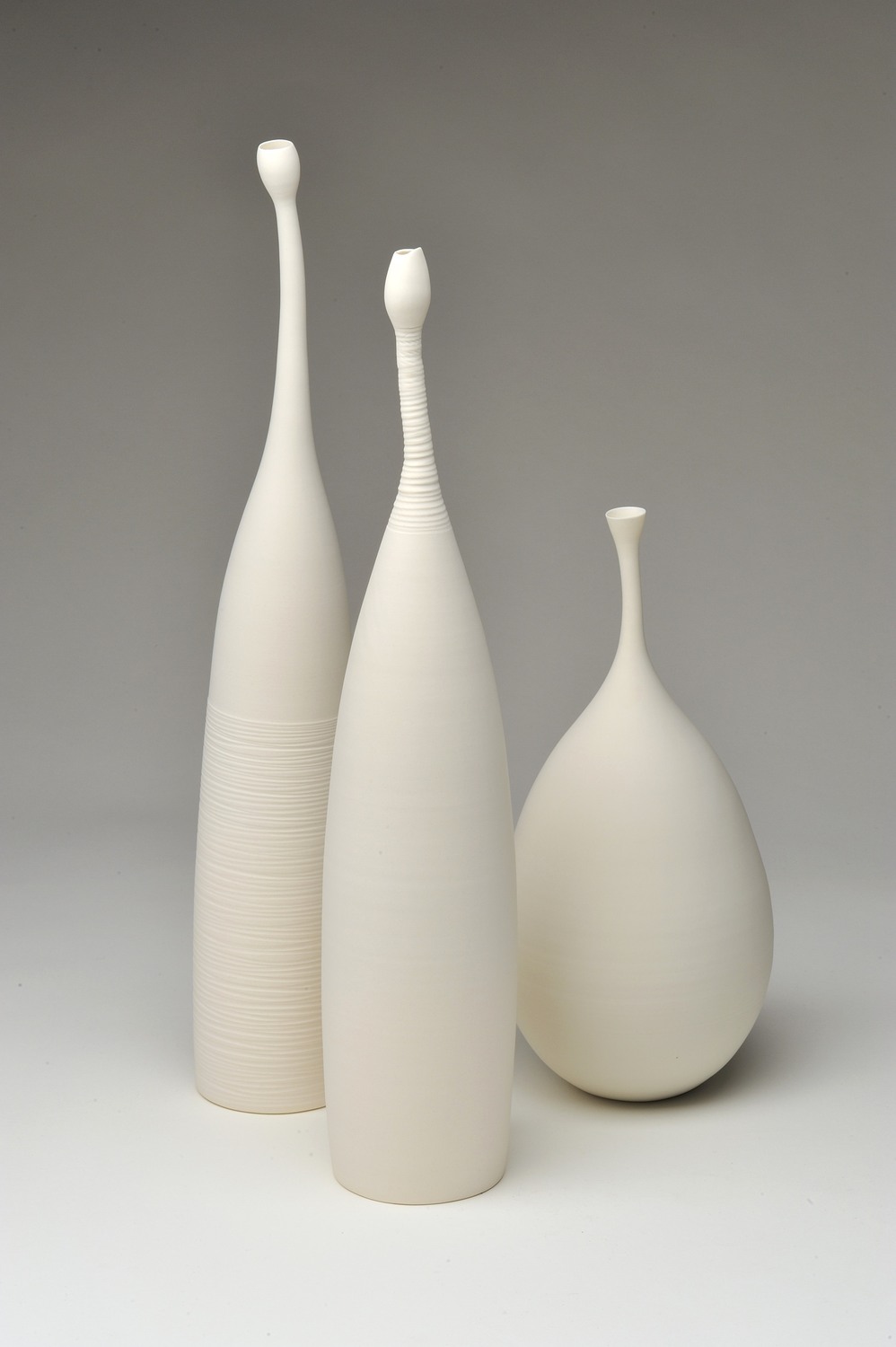 3 Flaschobjekte 1 - Deutsche Manufakturenstrasse Drei weiße Flaschenobjekte in unterschiedlichen Formen und Höhen auf einem neutralen Hintergrund.