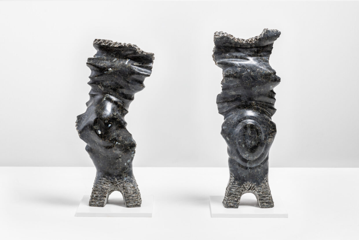 C Traub ENTFALTUNG 1+2 Labradorit je48cm hoch 1 - Deutsche Manufakturenstrasse Zwei abstrakte Skulpturen aus Labradorit, jeweils 48 cm hoch, auf einem weißen Sockel präsentiert.