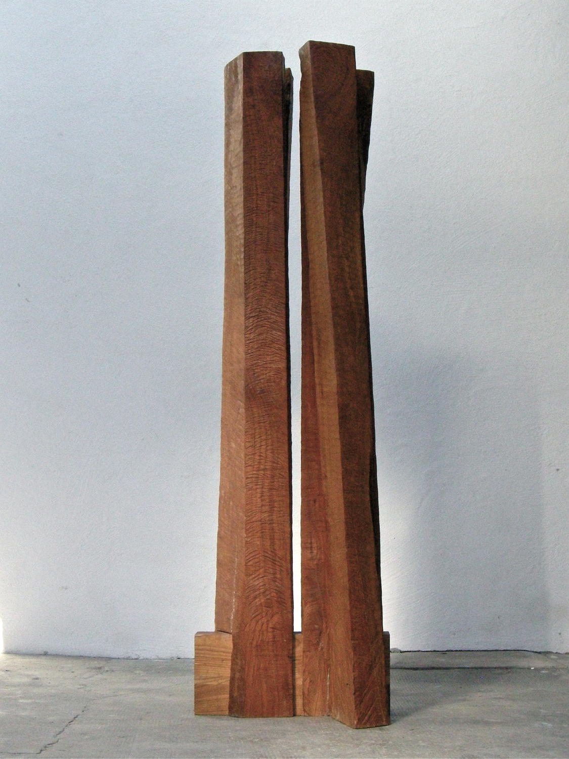Douma_In between 1 - Deutsche Manufakturenstrasse Zwei hohe, schmale Holzskulpturen stehen aufrecht nebeneinander, mit einer rauen, strukturierten Oberfläche.