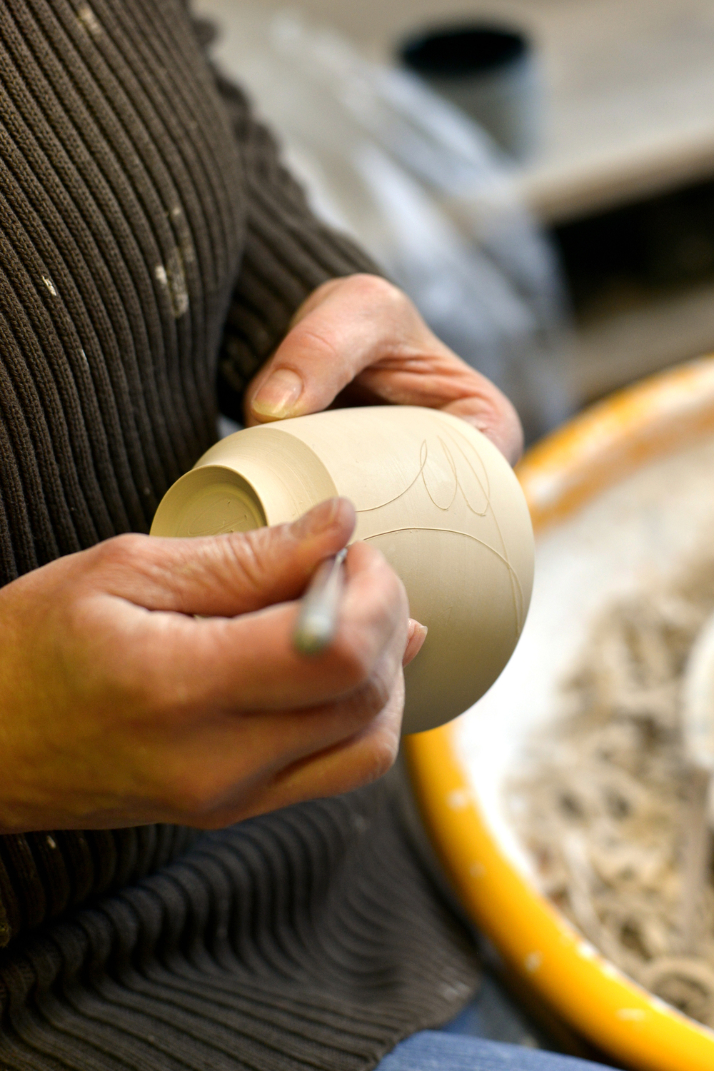 Inlay ritzen 1 - Deutsche Manufakturenstrasse Hände ritzen ein dekoratives Muster in einen ungebrannten Keramikbecher.