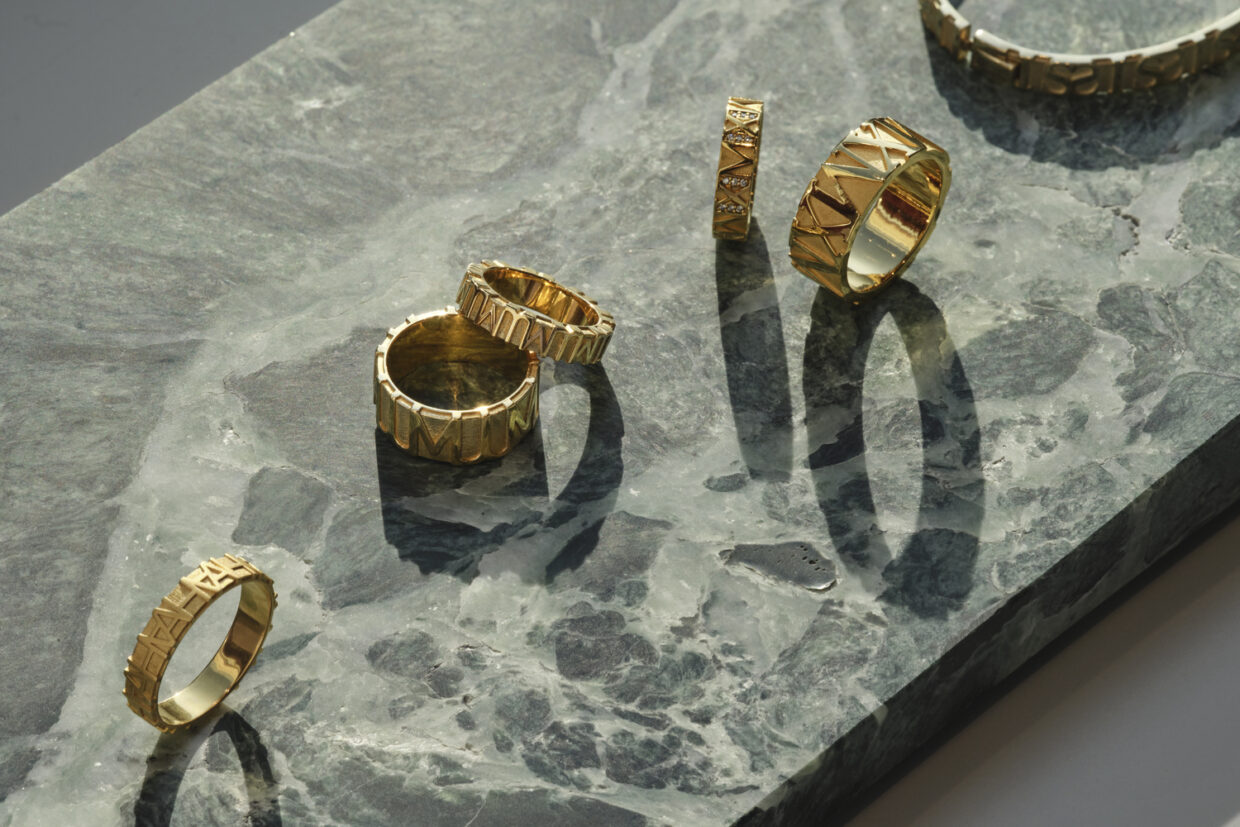 JJ_Showroom-Manufaktur_Feb2023_3239+ - Deutsche Manufakturenstrasse Goldene Ringe und ein Armband auf einer marmorierten grünen Oberfläche, mit langen Schatten im Sonnenlicht.