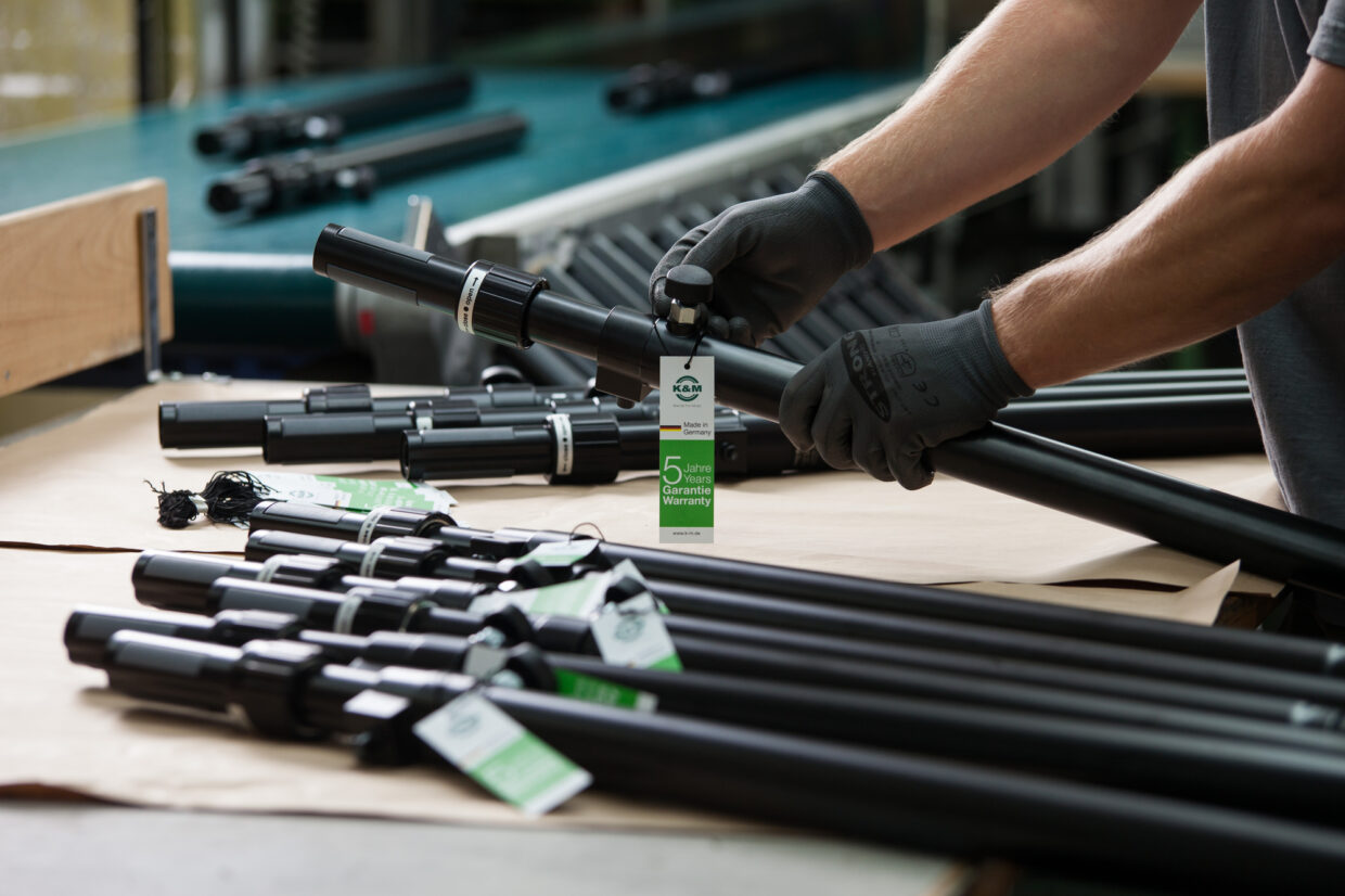 KM_003 1 - Deutsche Manufakturenstrasse Arbeiter montiert Mikrofonständer mit Etiketten in einer Produktionsumgebung bei König + Meyer.