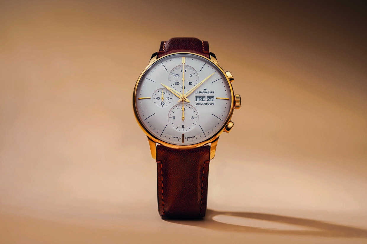 Elegante Junghans Meister Chronoscope Uhr mit silbernem Zifferblatt und braunem Lederarmband auf sanftem Hintergrund.