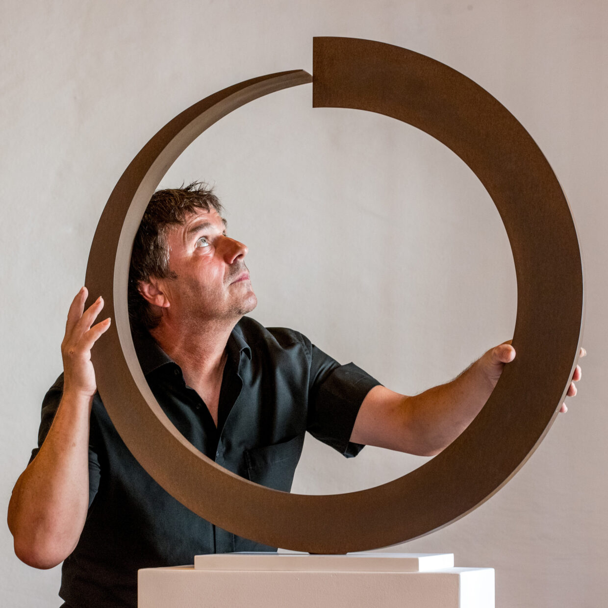 Künstler Rüdiger Seidt betrachtet eine kreisförmige Skulptur während seiner Ausstellung in Kempten.