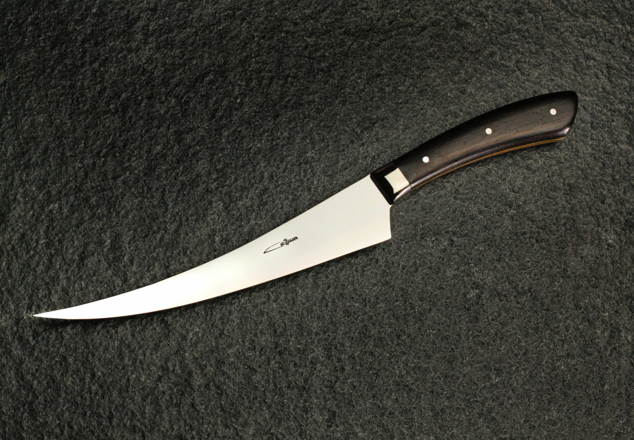 albMesser Filet Big Special 1 - Deutsche Manufakturenstrasse Elegantes Filetmesser mit gebogener Klinge und schwarzem Griff auf dunklem Hintergrund.