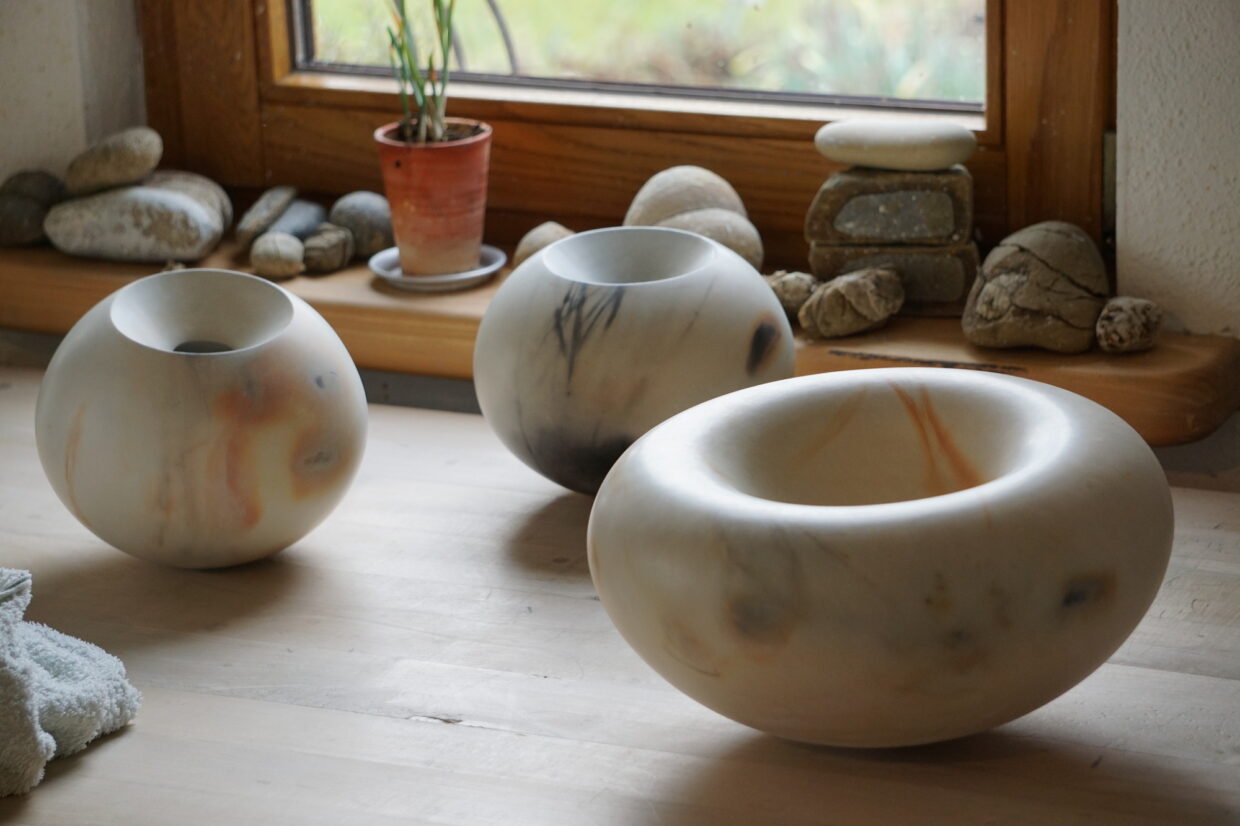 aus dem Holzfeuer gewaschen in der Werkstatt 1 - Deutsche Manufakturenstrasse Drei handgefertigte Schalen aus Holz, unterschiedlich groß, auf einem Tisch in einer Werkstatt, mit Pflanzen und Steinen ...