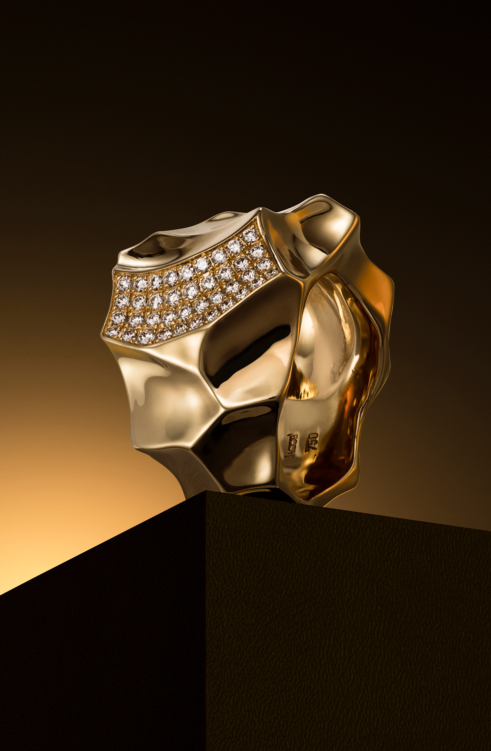 Ring750Roségold_Brillanten - Deutsche Manufakturenstrasse Eleganter Ring aus 750er Roségold mit Brillanten, auf einem schwarzen Sockel vor einem goldenen Hintergrund.